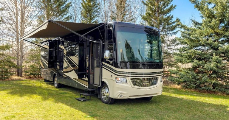 Class A motorhome with slide-outs and awning extended at a grassy campsite