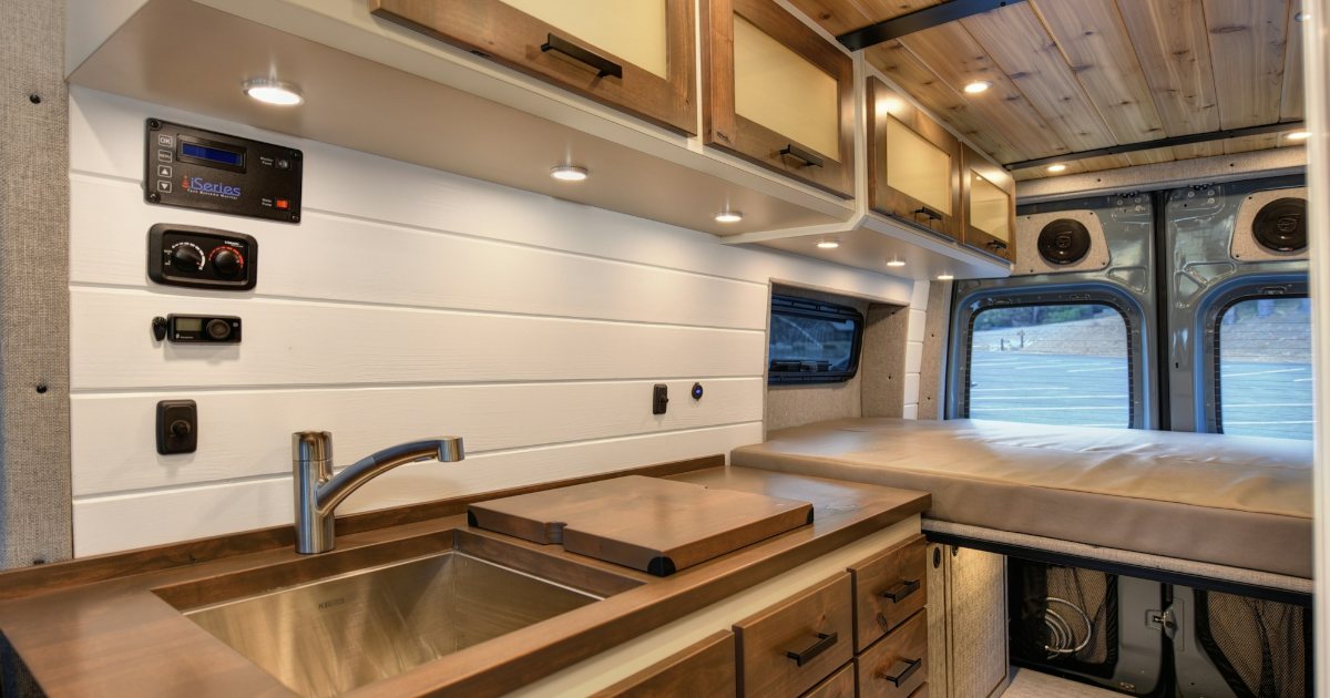 Organized camper van kitchen with overhead cabinets, sink and drawers